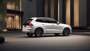 A Volvo XC60 in a showroom, with spotlights highlighting its blue metallic paint and sporty stance.